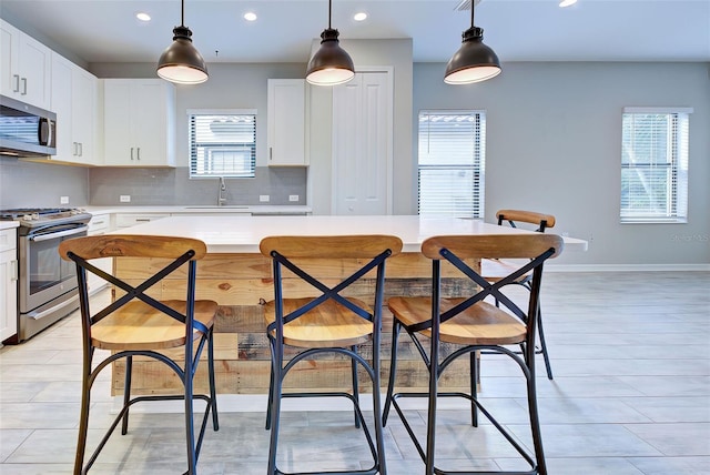 kitchen featuring hanging light fixtures, white cabinetry, sink, and stainless steel appliances