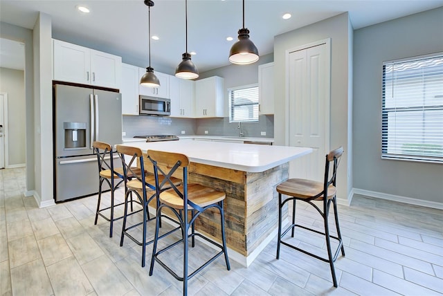 kitchen featuring appliances with stainless steel finishes, sink, pendant lighting, white cabinets, and a center island