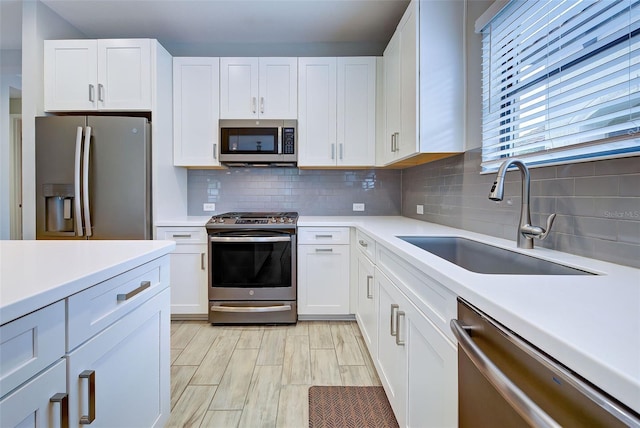 kitchen featuring white cabinets, stainless steel appliances, tasteful backsplash, and sink