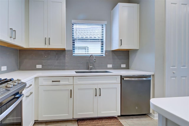 kitchen featuring white cabinetry, sink, stainless steel dishwasher, decorative backsplash, and range