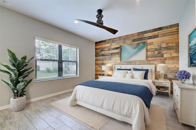 bedroom with wood walls, ceiling fan, and light hardwood / wood-style floors