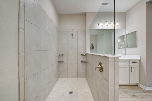 bathroom with tiled shower and vanity