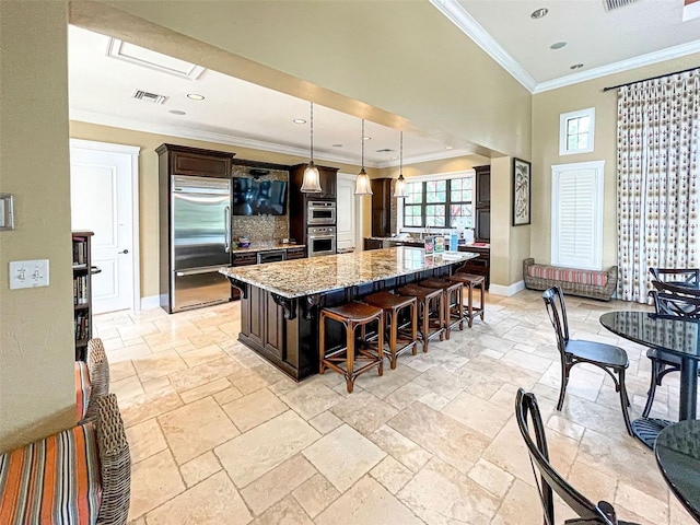 kitchen featuring a center island, stainless steel appliances, a kitchen breakfast bar, light stone counters, and pendant lighting