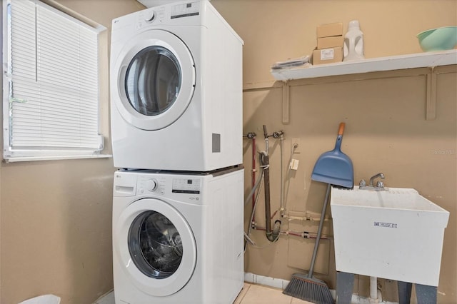 laundry area with light tile patterned floors, sink, and stacked washer and clothes dryer