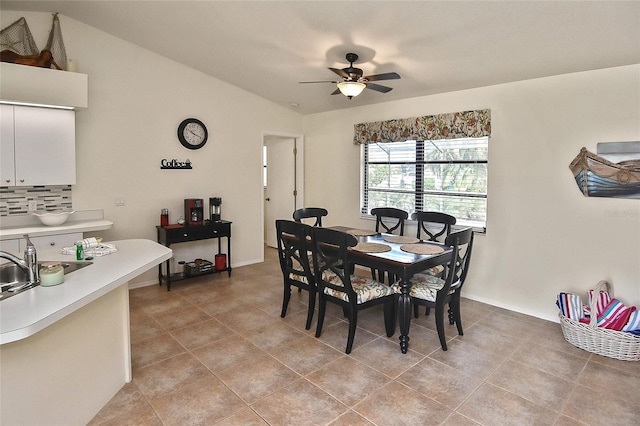 tiled dining space with sink, lofted ceiling, and ceiling fan