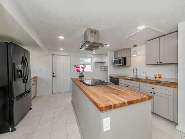 kitchen with black appliances, hanging light fixtures, butcher block countertops, a kitchen island, and light tile patterned floors