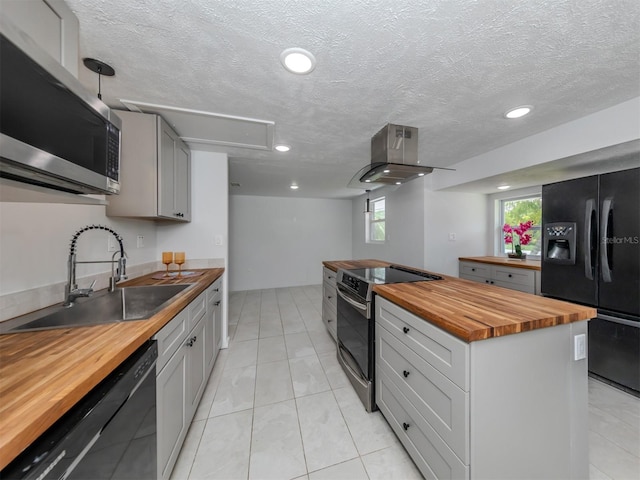 kitchen with light tile patterned flooring, wood counters, black appliances, island range hood, and sink