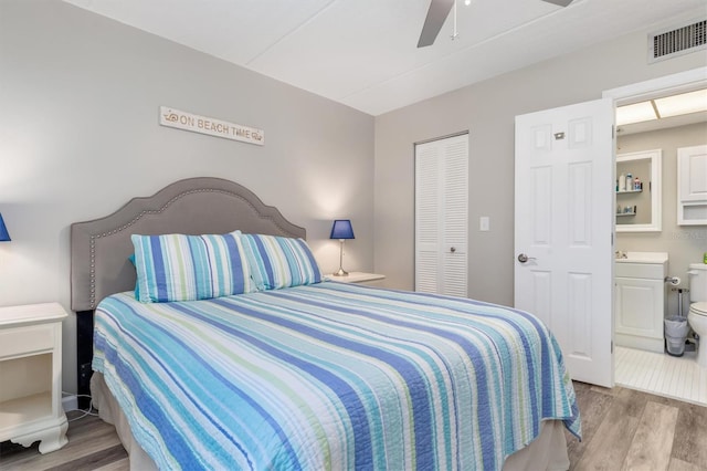 bedroom featuring ceiling fan, ensuite bath, a closet, and light hardwood / wood-style flooring