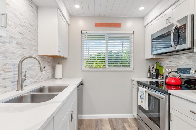 kitchen with white cabinets, backsplash, appliances with stainless steel finishes, and sink