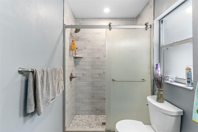 bathroom with a shower with door and toilet