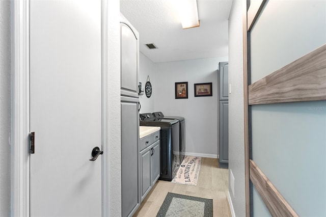 laundry room featuring light hardwood / wood-style floors, cabinets, and separate washer and dryer