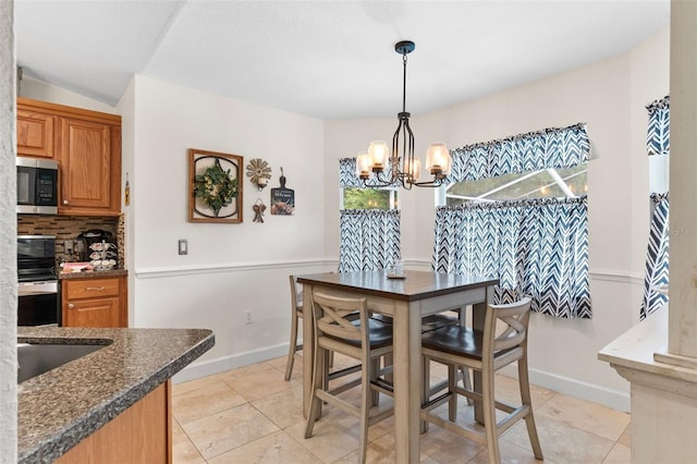 dining room with sink, vaulted ceiling, an inviting chandelier, and light tile patterned floors