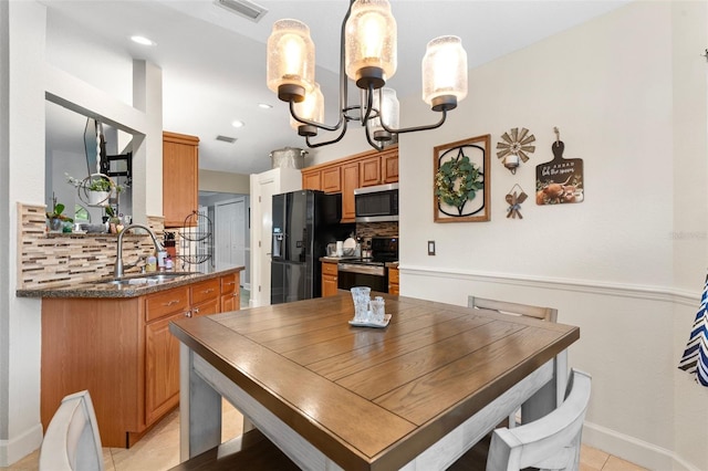 dining area featuring sink, a notable chandelier, and light tile patterned floors