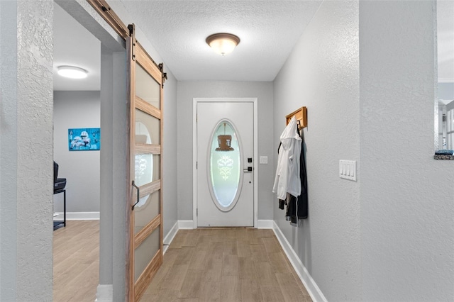 doorway to outside featuring light hardwood / wood-style floors, a textured ceiling, and a barn door