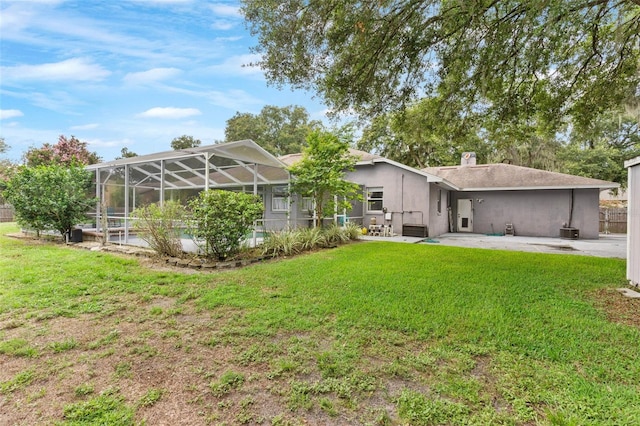 back of house with a patio area, a lawn, and a lanai