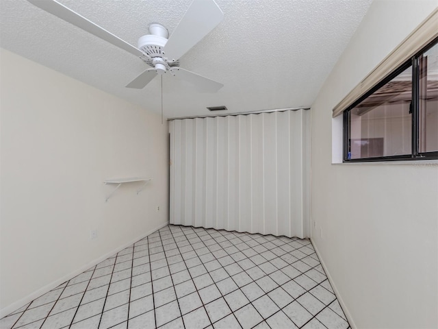 tiled empty room with a textured ceiling and ceiling fan