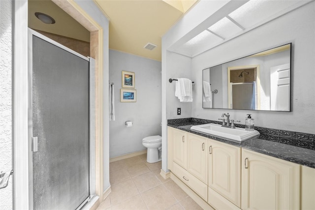 bathroom with a shower with door, toilet, vanity, and tile patterned flooring