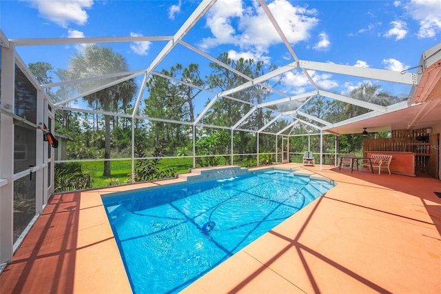 view of pool with glass enclosure and a patio area