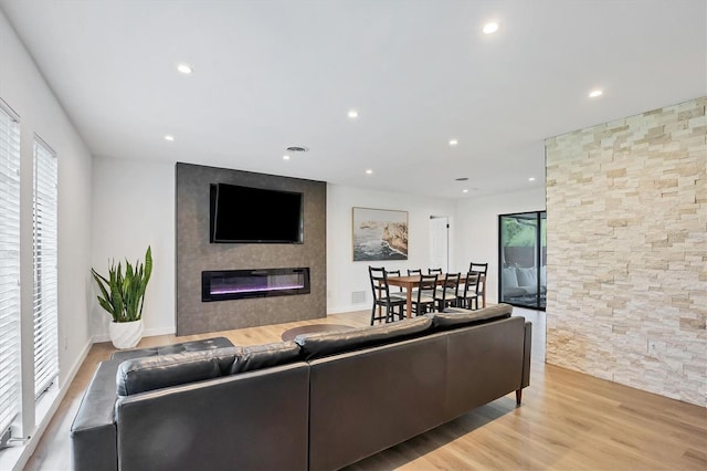 living room featuring plenty of natural light, a large fireplace, and light hardwood / wood-style flooring