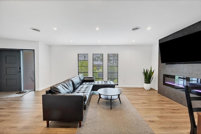 living room featuring a tiled fireplace and light hardwood / wood-style flooring