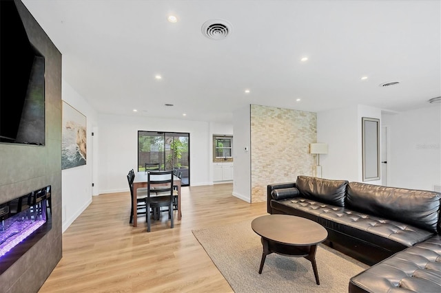 living room with a tiled fireplace and light hardwood / wood-style flooring