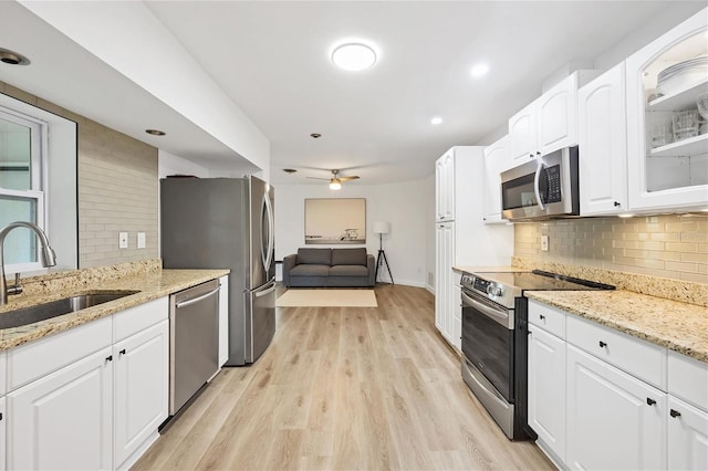 kitchen featuring sink, white cabinetry, light stone counters, stainless steel appliances, and backsplash