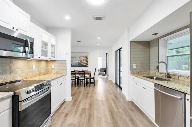 kitchen featuring sink, light stone countertops, white cabinets, and appliances with stainless steel finishes