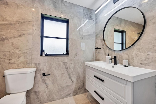 bathroom with tile walls, vanity, and toilet