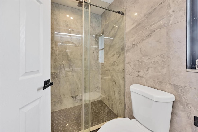 bathroom with tile walls, toilet, and walk in shower