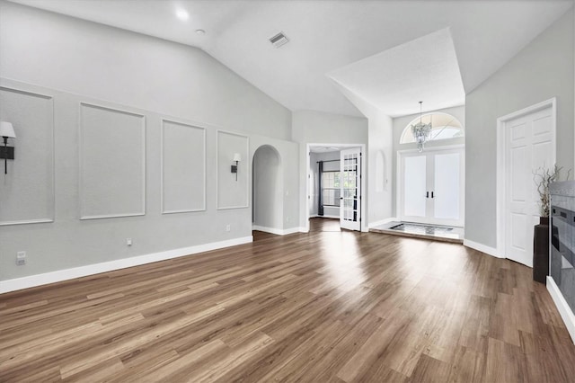 unfurnished living room with hardwood / wood-style flooring, french doors, and high vaulted ceiling