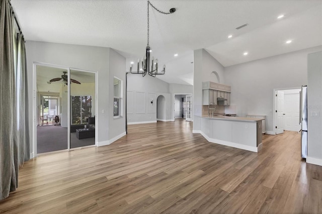 kitchen with kitchen peninsula, sink, stainless steel fridge, and wood-type flooring