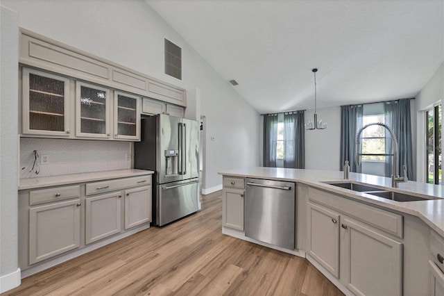 kitchen with pendant lighting, sink, decorative backsplash, lofted ceiling, and stainless steel appliances