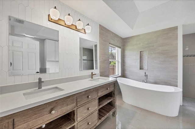 bathroom featuring tile patterned floors, vanity, tile walls, a bath, and a tray ceiling