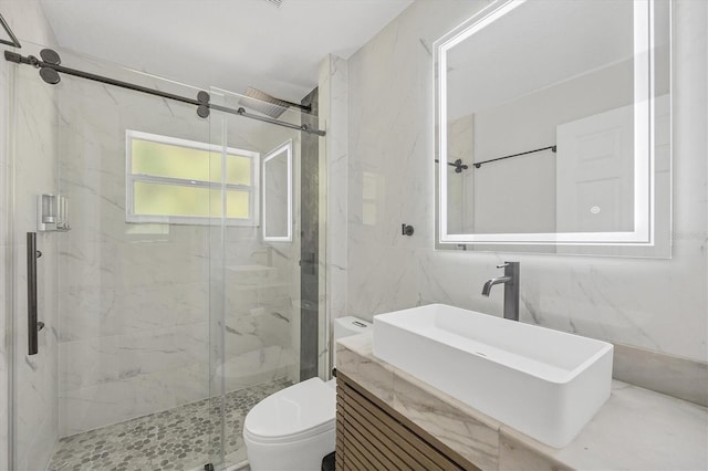 bathroom featuring toilet, a shower with shower door, vanity, and tile walls