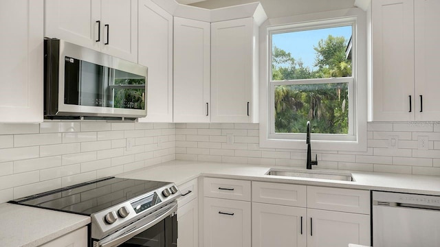 kitchen featuring stainless steel appliances, sink, white cabinetry, tasteful backsplash, and a healthy amount of sunlight