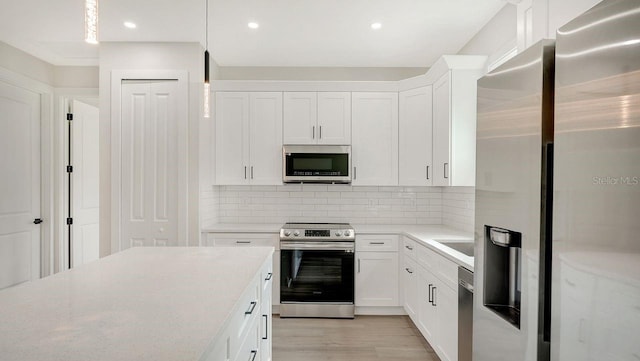 kitchen featuring light hardwood / wood-style flooring, white cabinets, pendant lighting, stainless steel appliances, and backsplash