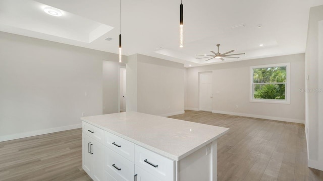 kitchen with pendant lighting, a tray ceiling, white cabinetry, and ceiling fan