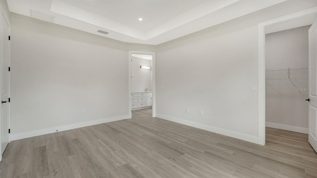 empty room featuring a raised ceiling and light wood-type flooring