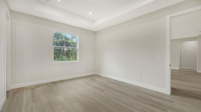 spare room featuring light hardwood / wood-style floors and a tray ceiling