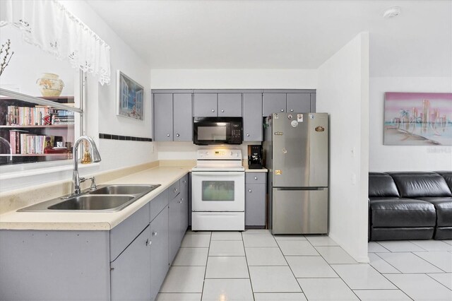 kitchen with gray cabinetry, stainless steel refrigerator, sink, electric stove, and light tile patterned flooring