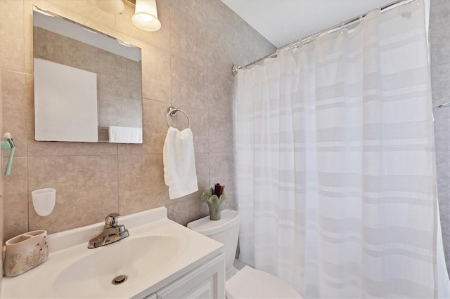 bathroom with tile walls, walk in shower, toilet, and vanity