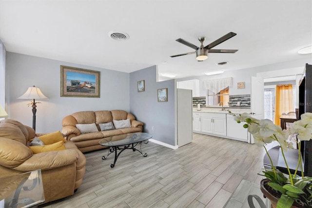 living room with light wood-type flooring, sink, and ceiling fan