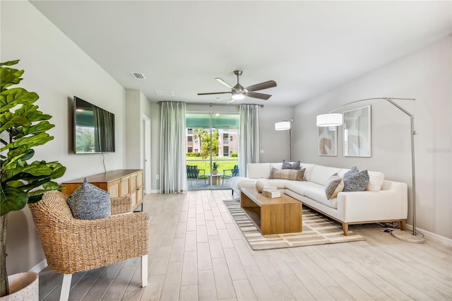 living area featuring light wood-type flooring, visible vents, ceiling fan, and baseboards