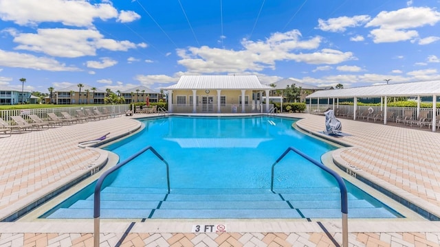 pool with a patio, fence, and a residential view