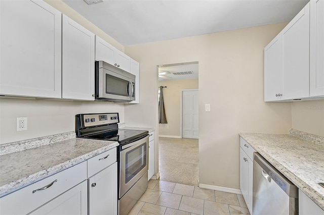 kitchen with white cabinetry, stainless steel appliances, light carpet, and light stone countertops