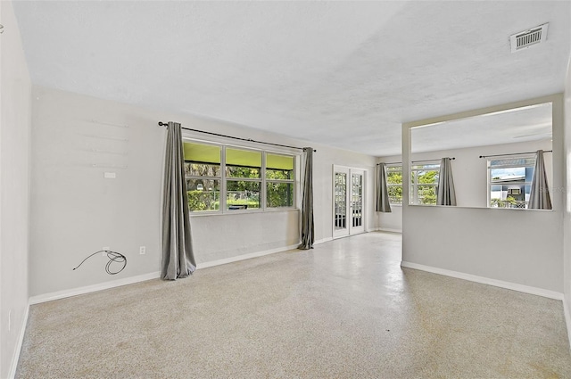 empty room featuring french doors and a textured ceiling