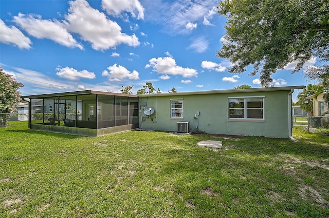 rear view of property featuring central AC, a sunroom, and a lawn