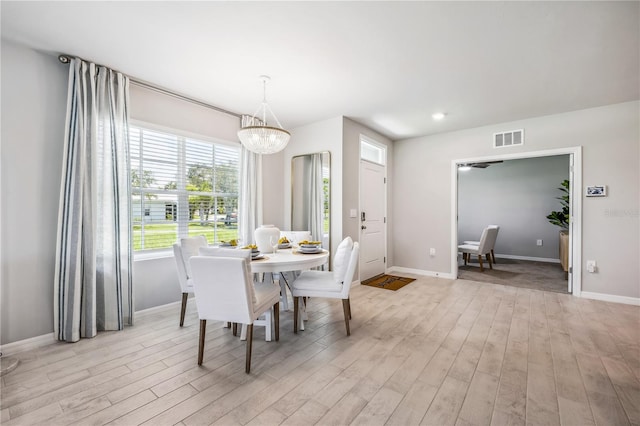 dining space with an inviting chandelier and light hardwood / wood-style flooring