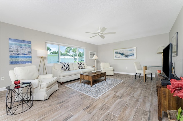 living room featuring ceiling fan and a textured ceiling