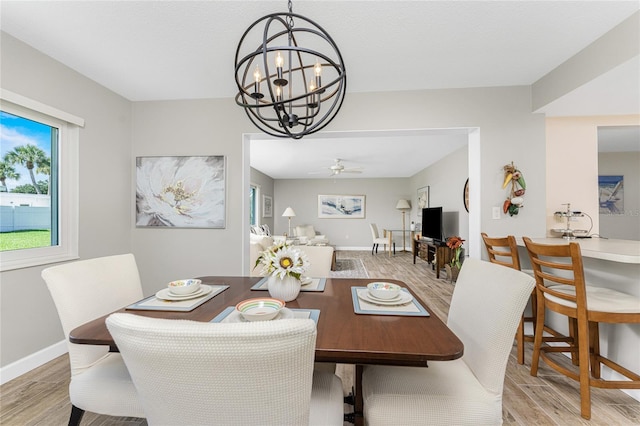 dining space with ceiling fan with notable chandelier and light wood-type flooring